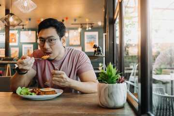Asian men with a beard wear eyeglasses and enjoy eating in the restaurant.
