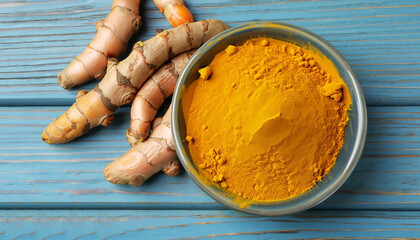 Bowl with turmeric powder and raw roots on blue wooden table, flat lay