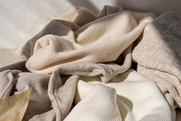 Messy crumpled warm wool and cotton neutral beige pastel knitted clothes, knitwear in sunlight with...