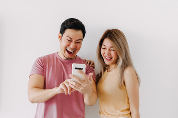 Happy asian couple lover laughing at the news content in the smartphone isolated on white.