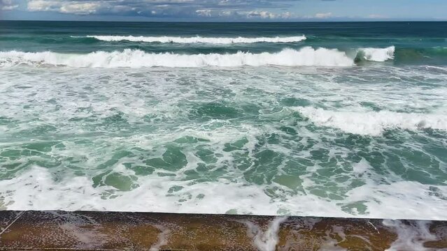 HD Video -Waves crashing on the sea wall at North Cronulla Beach in Sydney, Australia. Due to coastal erosion and following a severe storm in June 2022, the ocean reached close up to the sea wall.