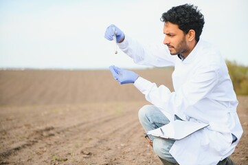 Soil Testing. Indian Agronomy Specialist taking soil sample for fertility analysis. Hands in gloves...