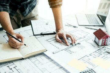 Interior designer or architect reviewing blueprints and holding pencil drawing on desk at home office. - 632004338