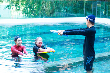 Elderly people doing physical therapy in water There are male and female staff teaching...
