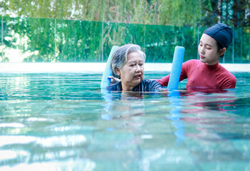 Elderly person doing physiotherapy in water. Female staff doing physiotherapy for seniors. exercise...