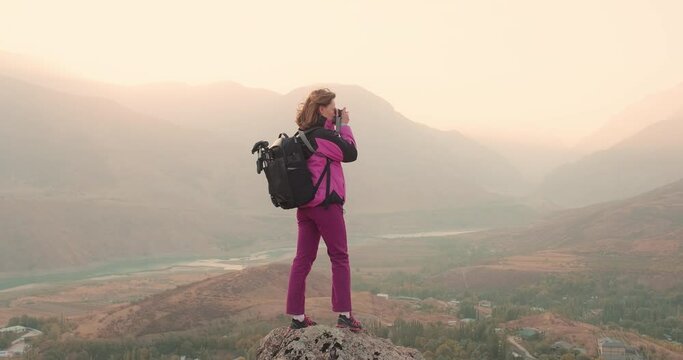 Woman taking photo of mountains landscape during hiking. Healthy, active lifestyle and outdoor leisure time concept