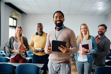 Happy black professor and his adult students in lecture hall looking at camera.