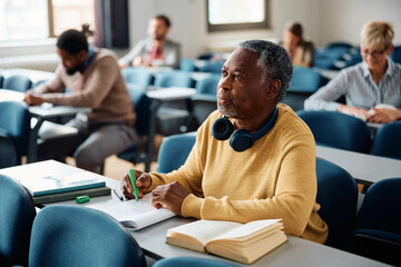 Black senior man student during lecture in classroom.