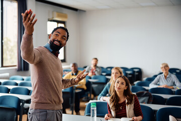 Happy black professor teaching group students during adult education training course in lecture...
