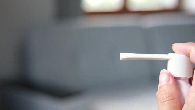 Human hand spraying throat flu spray from dispenser