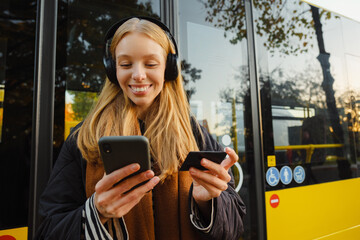 Woman shopping tickets online with mobile phone and credit card while standing at bus station