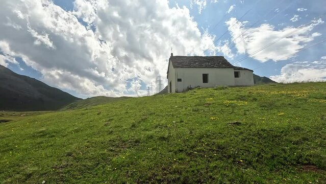 Approaching a white chapel in the alps of switzerland on a green summer meadow . San Giacomo