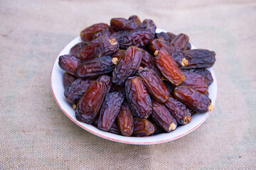 One bowl delicious Date fruits on the jute fiber fabric