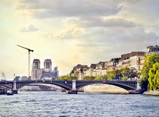 A bridge crosses the Seine river in Paris, with Notre Dame in the background.