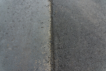 A large layer of fresh asphalt in the town.Layer of asphalt raw material in a shallow depth of field. Road construction. Construction of a new road.