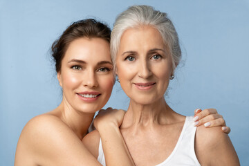 Smiling woman hugs joyful elderly mother by the shoulders. Beauty portrait of beautiful women of...