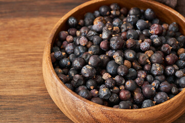 dry juniper berry seed in wood plate on wooden table background. dry juniper berry seed background. heap of dry juniper berry seed food background                          