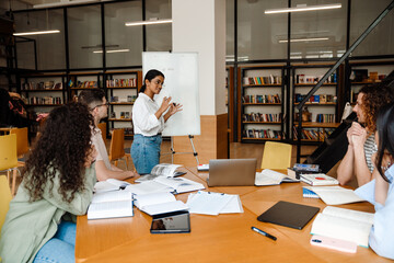 Young woman making presentation for students at whiteboard in library
