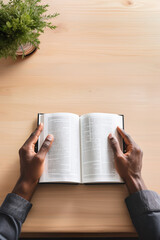 Fototapeta premium Man's hands holding an opened book on the wooden table