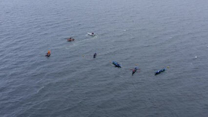 Static aerial view of currach boats above buoys in open ocean water