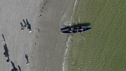 Drone top down perspective follows people in currach rowing boats into open ocean water