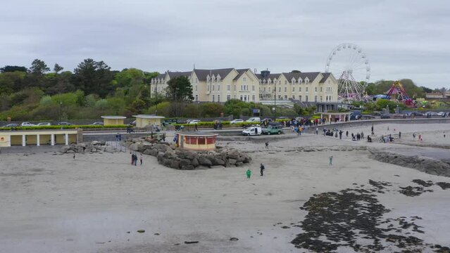 People walk along salthill promenade and enjoy beautiful irish day at ladies beach galway
