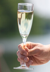 A glass of champagne in the hand of a man in nature. Close-up