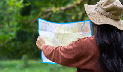 Active young woman holding a map while taking a hiking break, having fun and relaxing