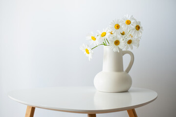 wildflowers in white jug on white background