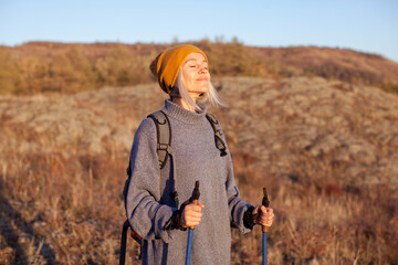 Middle aged woman hiking and going camping in autumn forest - obrazy, fototapety, plakaty
