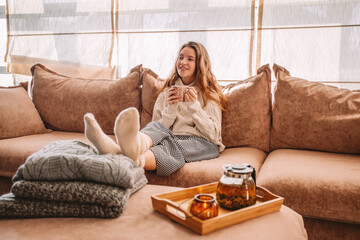 Happy woman relaxing on sofa at home on bright winter morning - 632034715