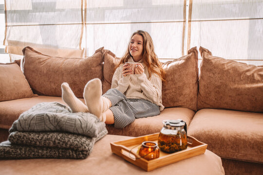 Happy woman relaxing on sofa at home on bright winter morning