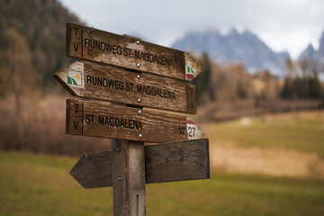 Scenic view of the Dolomites, Italy. Wooden signpost in front of rough Alpine mountain range in the background. Concept of hiking adventures.