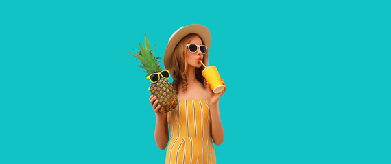 Summer portrait of young woman drinking fresh juice and holding pineapple wearing straw hat,...