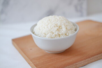 Cooked rice in a white bowl on a wooden board. Selective focus.