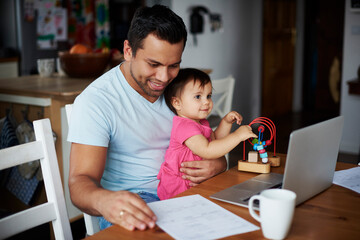 Father with baby girl using laptop on table at home
