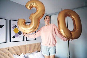 Portrait of cheerful woman with golden balloons, celebrating her birthday