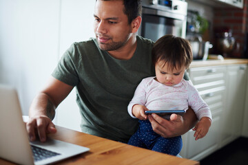 Father using laptop with baby girl using smartphone at home