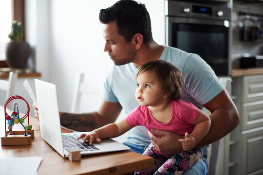 Father with baby girl using laptop on table at home