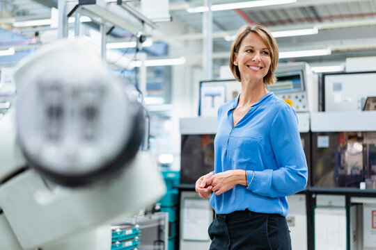 Portrait of businesswoman at assembly robot in a factory