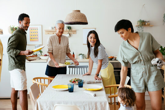 Smiling family setting table in kitchen