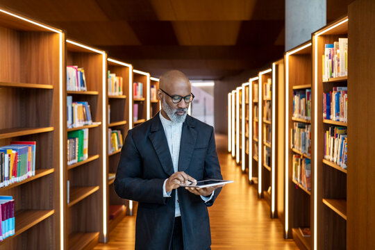 Mature businessman using digital tablet at library