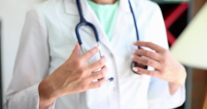 Doctor folds hands and adjusts stethoscope in clinic. Medical therapist cardiologist and health insurance