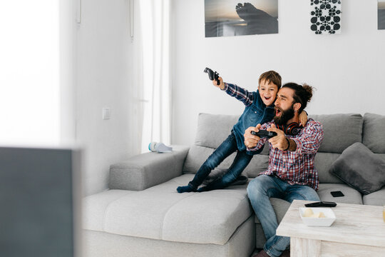Father and son playing computer game together at home