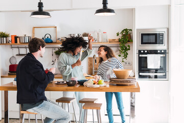 Happy family preparing food together singing and dancing in the kitchen