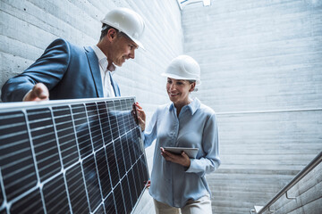 Happy engineers discussing over solar panel