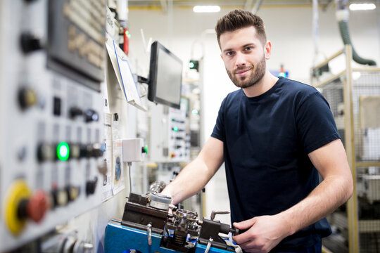 Portrait of a confident man working in a modern factory at a machine