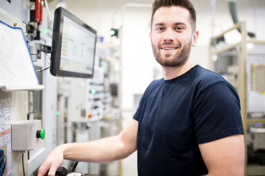 Portrait of a confident man working in a modern factory at a machine