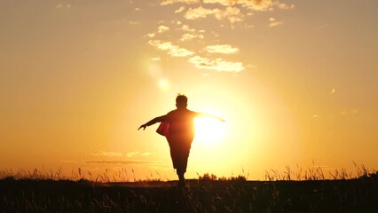Silhouette superhero. A super kid hero runs with his arms outstretched. The child dreams of victory, freedom runs up the mountain.