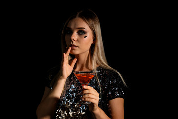 A girl at a party in the style of Halloween with a cocktail in her hands